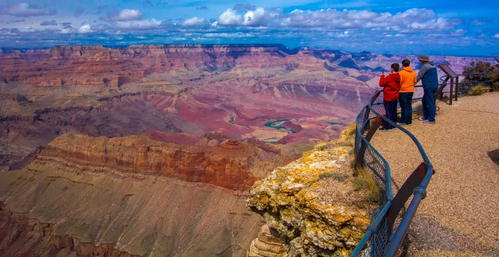 Three people admiring the vista at a Grand Canyon lookout point